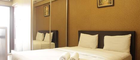 A hotel room with a bed, a large mirror, and a painting on the wall.