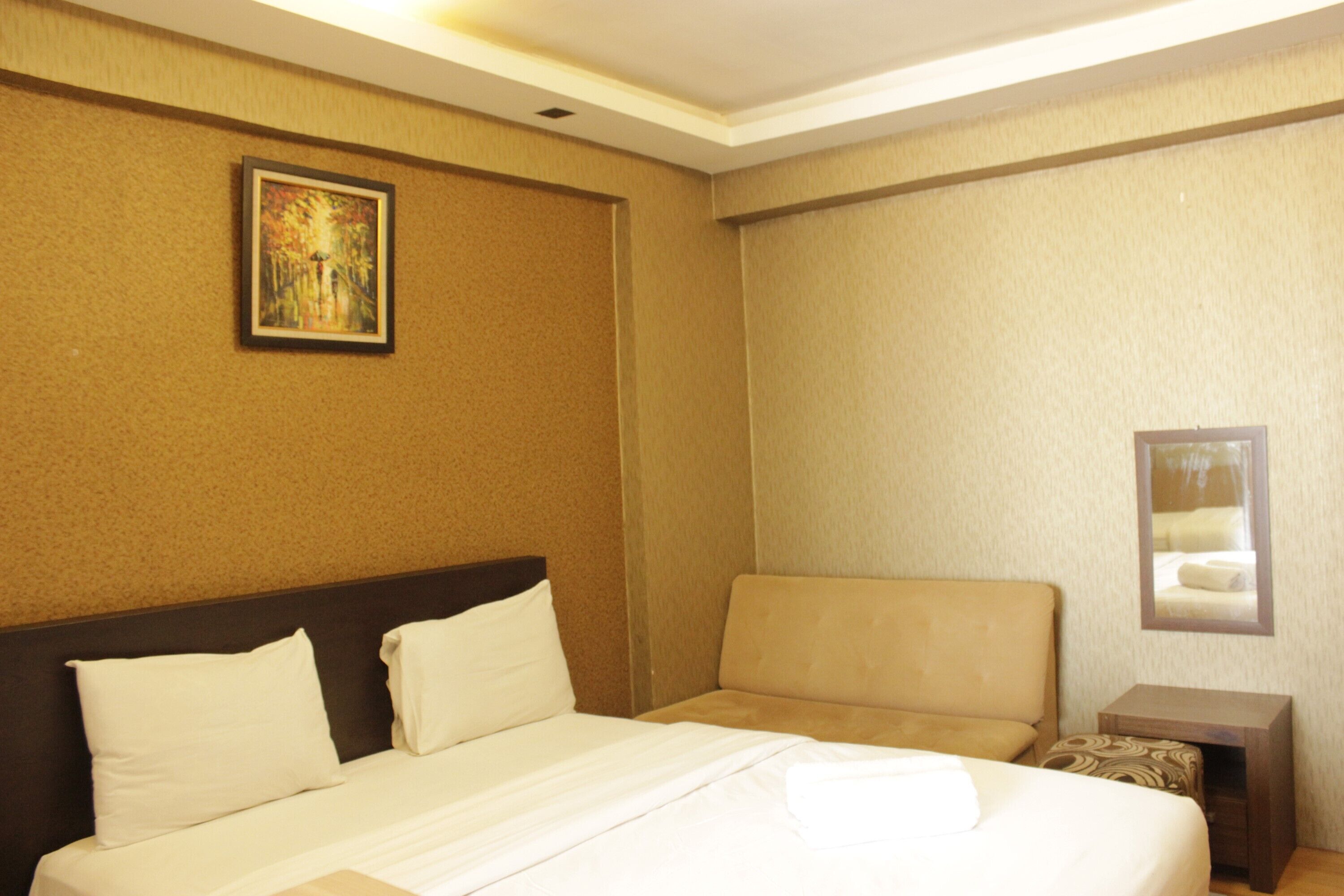 Una habitación de hotel con cama, sofá, una mesita y un cuadro en la pared.