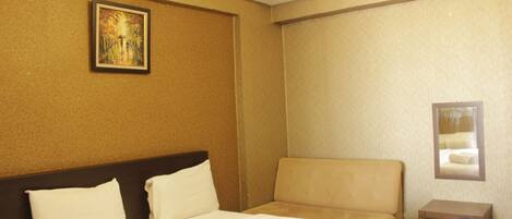 Una habitación de hotel con cama, sofá, una mesita y un cuadro en la pared.