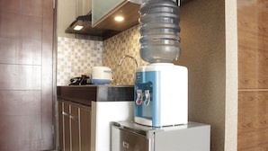 A kitchen with a water dispenser, a coffee maker, and a refrigerator.