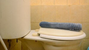 A toilet with a blue towel on the seat and a soap dispenser. - Cozy Studio Apartment at Margonda Residence 2 near Universitas Indonesia (Depok)