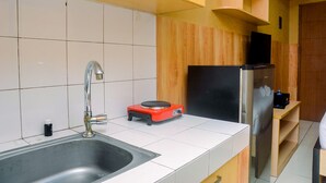 A kitchen with a stainless steel sink, a red electric stove, and a black refrigerator. - Cozy Studio Apartment at Margonda Residence 2 near Universitas Indonesia (Depok)