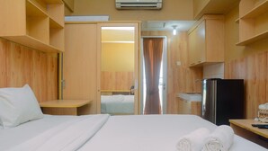 A hotel room with a bed, a desk, a refrigerator, and a mirror. - Cozy Studio Apartment at Margonda Residence 2 near Universitas Indonesia (Depok)