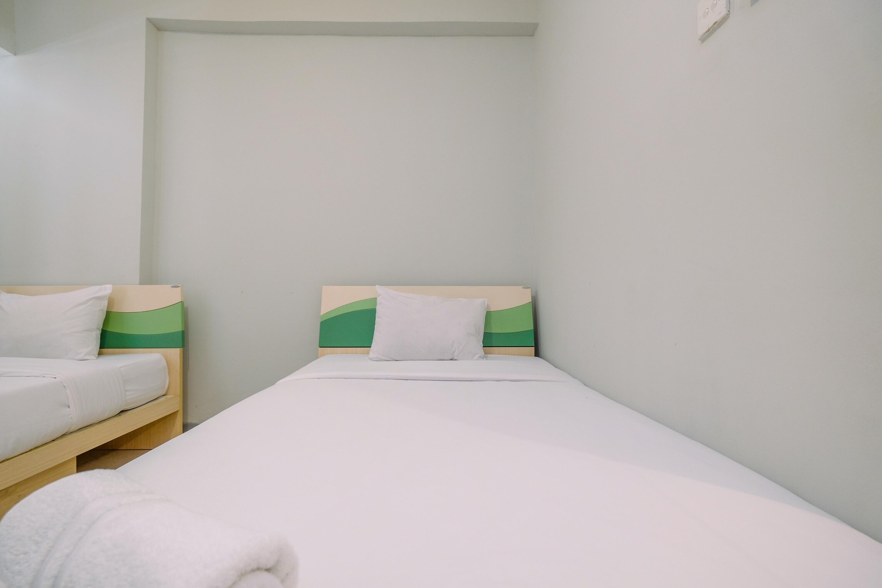 Una habitación pequeña y limpia con dos camas individuales, cada una con una almohada y un edredón.