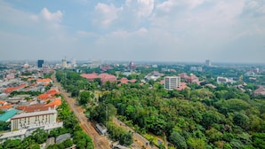 An aerial view of a cityscape with dense greenery, railway tracks, and various buildings. - Modern Studio Apartment at Taman Melati Margonda near Universitas Indonesia (Depok)