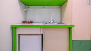 A compact kitchenette with a green countertop, a sink, and a small refrigerator. - Modern Studio Apartment at Taman Melati Margonda near Universitas Indonesia (Depok)