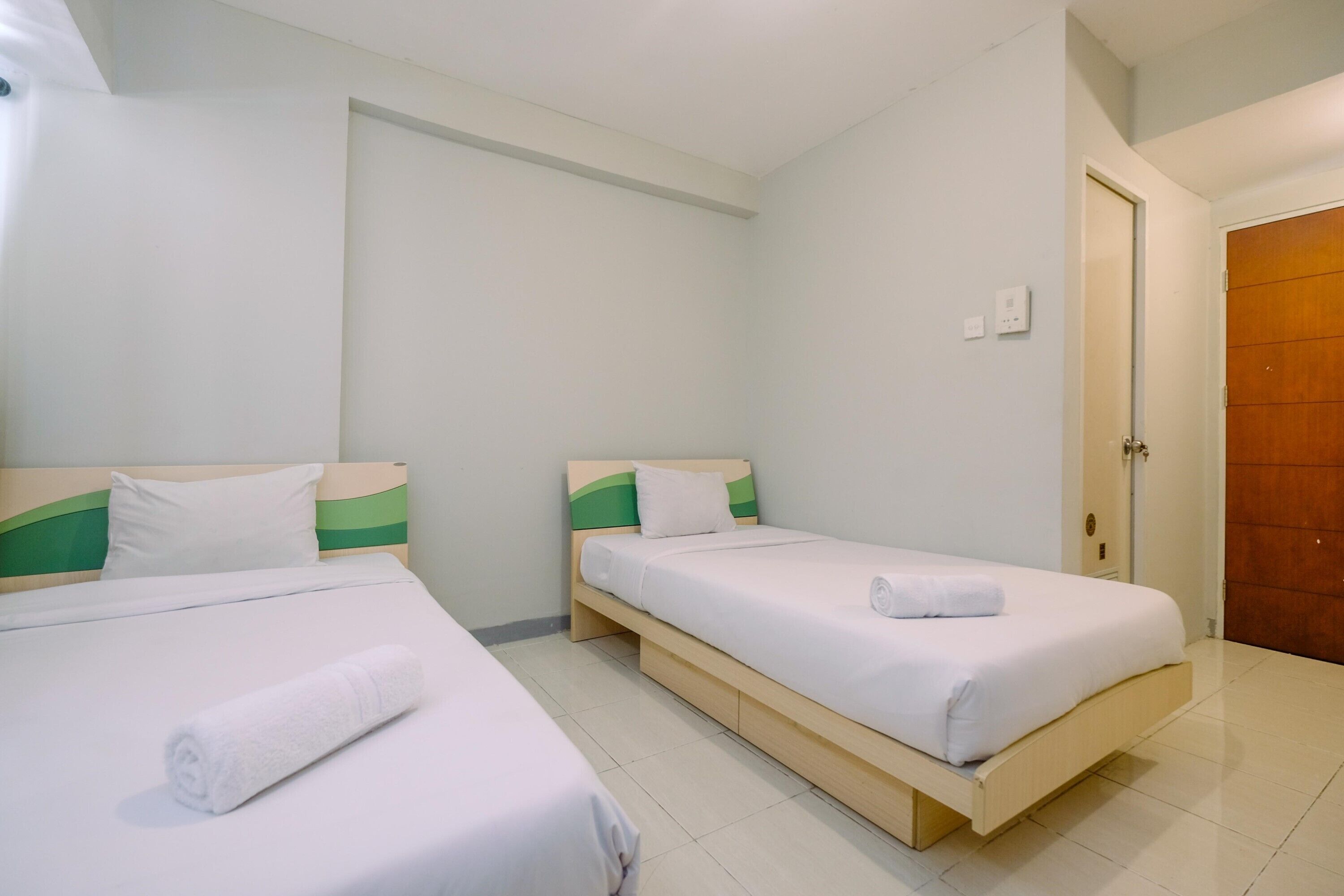 Una habitación de hotel con dos camas individuales, cada una con estructura de madera y ropa de cama blanca.