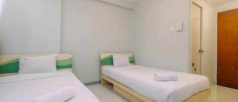 Una habitación de hotel con dos camas individuales, cada una con estructura de madera y ropa de cama blanca.