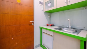 A compact kitchen with a sink, cabinets, and a wooden door. - Modern Studio Apartment at Taman Melati Margonda near Universitas Indonesia (Depok)