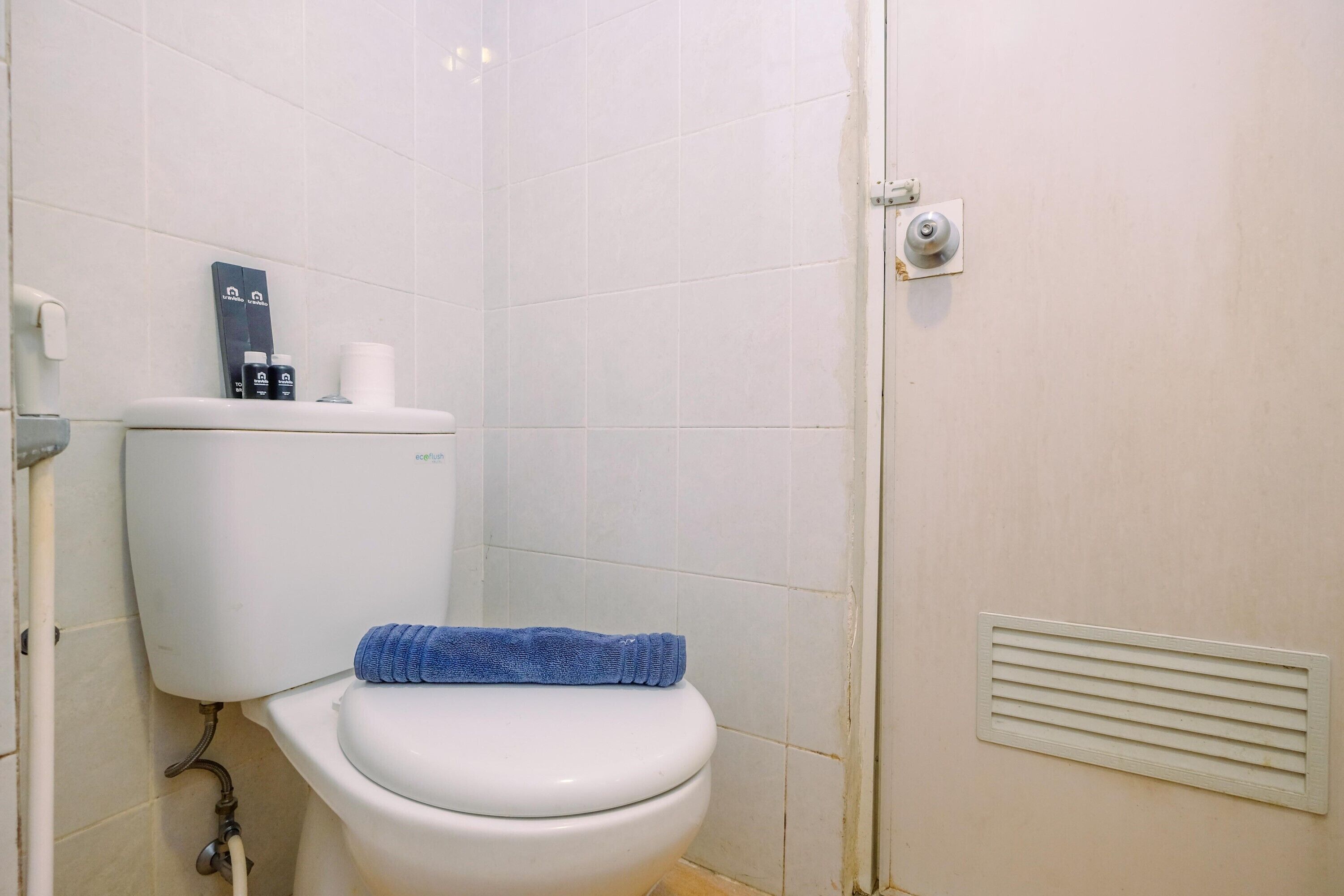 Un bagno con il water, un asciugamano e un portasciugamani.