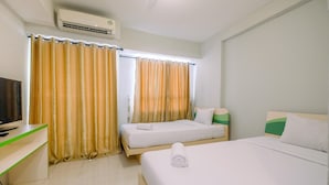 A hotel room with two beds, a TV, and an air conditioning unit. - Modern Studio Apartment at Taman Melati Margonda near Universitas Indonesia (Depok)