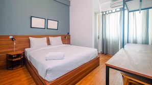 A modern hotel room with a wooden bed, a small bedside table, a desk, and a large window with curtains. - Modern Furnished @ 1BR Margonda Residence 1 Apartment (Depok)