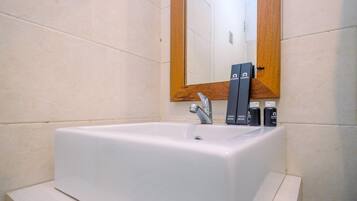 Uma casa de banho com uma pia branca, um espelho com moldura de madeira e duas escovas de dentes na pia.