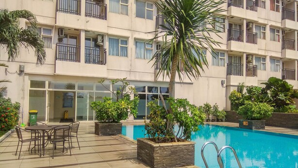 En bostadsbyggnad med en swimmingpool, utomhusmöbler och krukväxter.