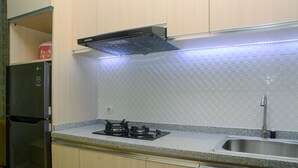 A kitchen with a refrigerator, stove, sink, and a microwave. - Fabulous 1BR Apartment at Atlanta Residences (Depok)