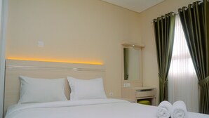 A neatly made bed with white linens, a bedside table with a mirror, and two rolled towels on the bed. - Fabulous 1BR Apartment at Atlanta Residences (Depok)