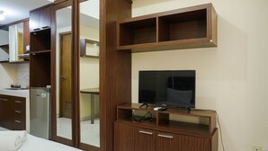 Une chambre d’hôtel avec une armoire en bois, une télévision et un miroir.