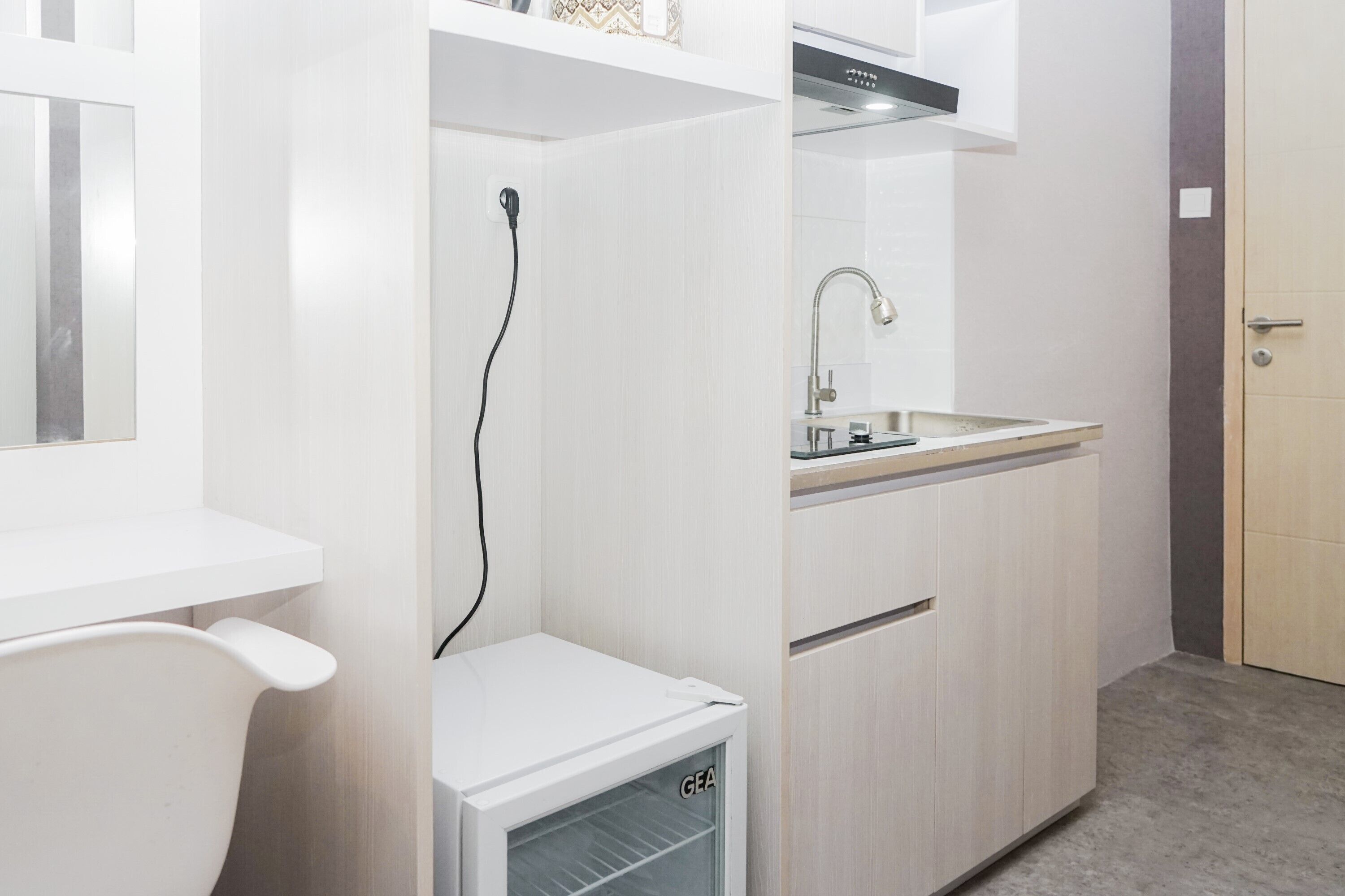 A compact kitchen with a built-in refrigerator, a sink, and a window.