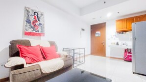 Ein Wohnzimmer mit einer Couch, einem Couchtisch und einer Küchenzeile mit Holzausstattung und einem Kühlschrank.