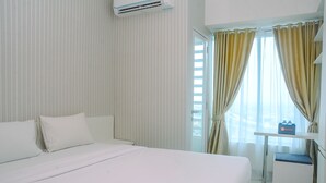A hotel room with a large bed, a bedside table, and a window with curtains. - New Furnished Studio Grand Kamala Lagoon Apartment (Bekasi)