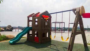A playground with a slide, swings, and a climbing structure. - New Furnished Studio Grand Kamala Lagoon Apartment (Bekasi)
