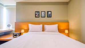Une chambre d’hôtel avec un grand lit, deux lampes de chevet, une tête de lit en bois et trois tableaux encadrés accrochés au mur.