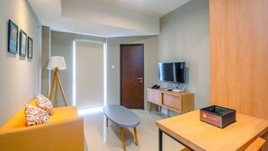 Un salon moderne comprenant un canapé, une petite table, un téléviseur et un meuble.