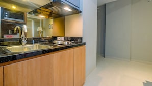 Une cuisine moderne dotée d’un plan de travail noir, d’un évier en acier inoxydable, de meubles en bois et d’un four à micro-ondes encastré.