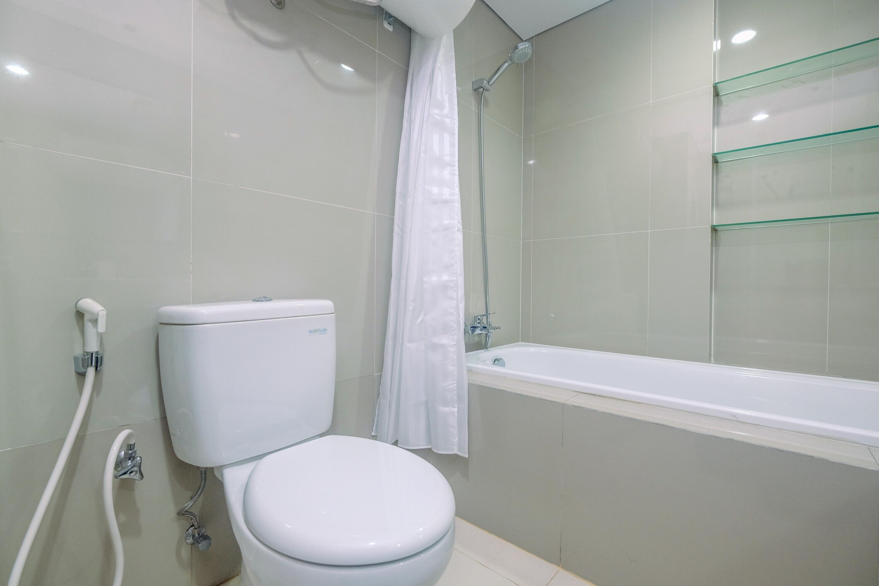 A bathroom with a toilet, shower, and glass shelves.