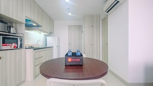 A modern kitchen with a microwave, kettle, and travel essentials on a table. - Stunning Studio Azalea Suites Apartment (Cikarang)