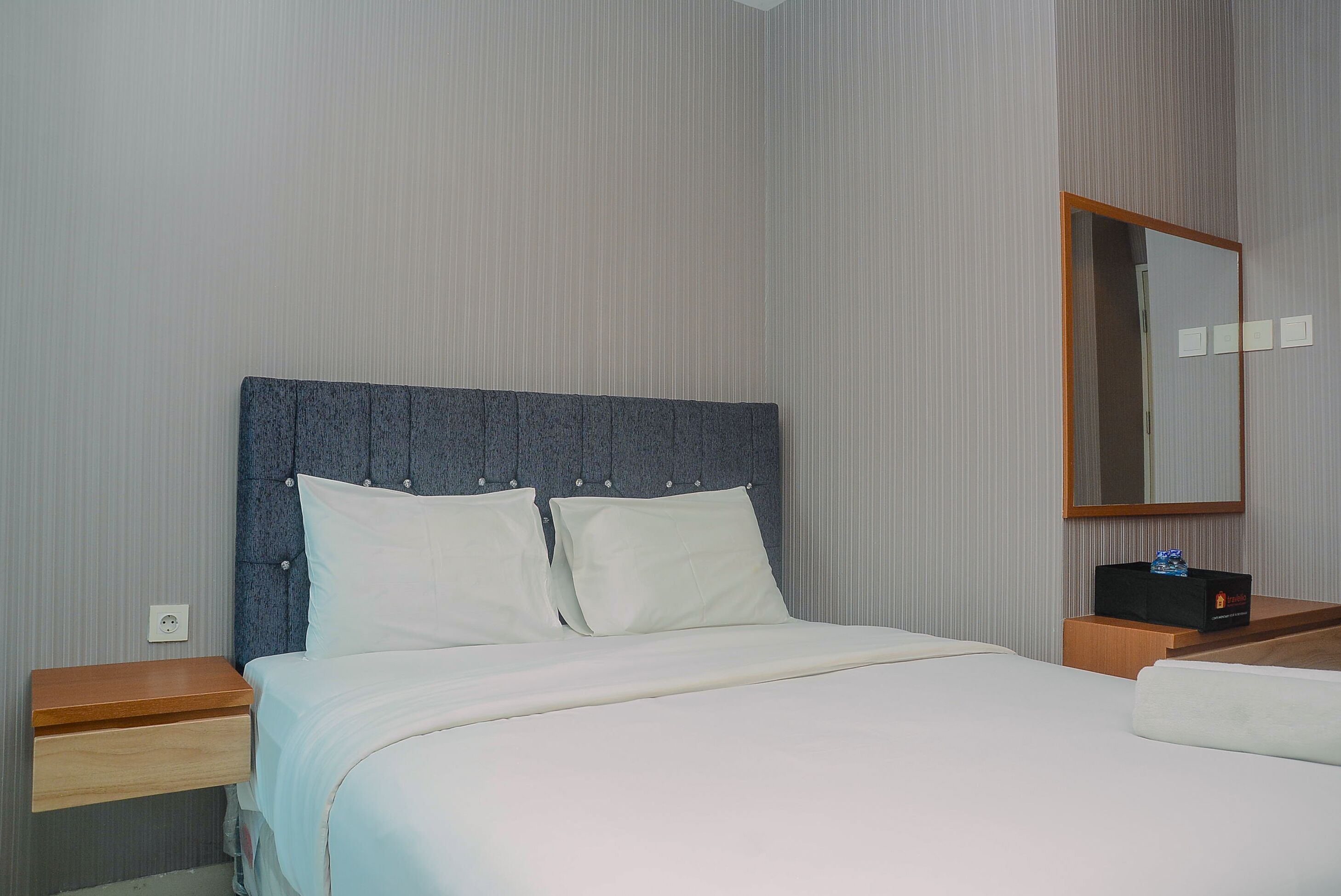 A neatly made bed with a headboard, a bedside table, and a nightstand.