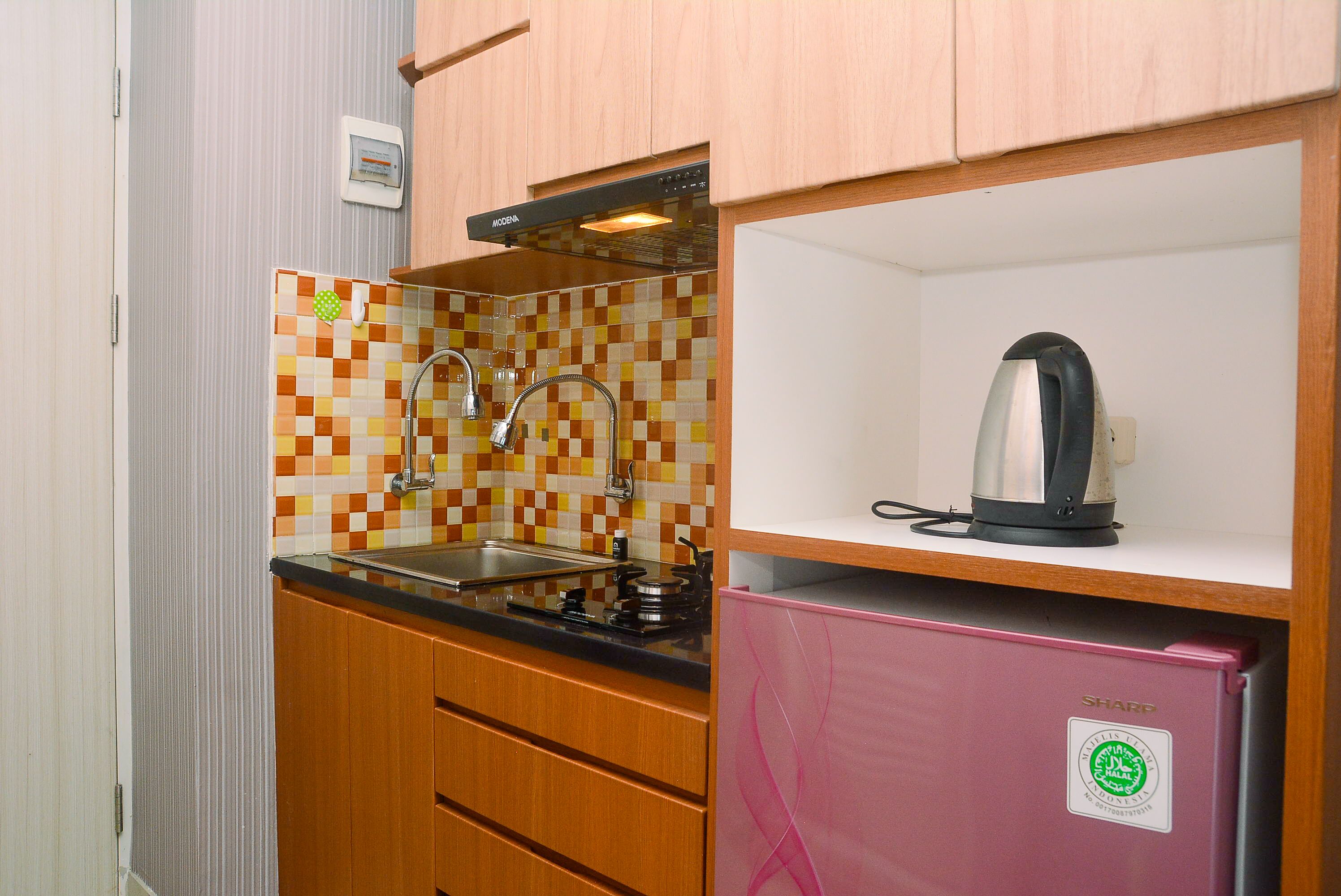 A compact kitchen with a tiled backsplash, a stainless steel sink, a gas stove, and a pink refrigerator.