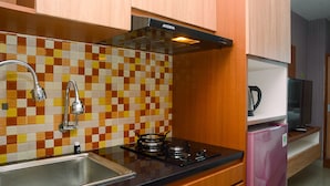 Cucina con zoccolo in piastrelle, piano cottura a gas, lavello e pensili in legno.