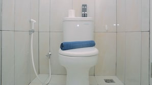 Un waterino bianco con un asciugamano blu sopra, una maniglia per lo sciacquone e un accessorio bidet.