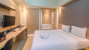 Une chambre d’hôtel équipée d’un lit, d’un bureau avec un ordinateur, d’une télévision et d’un mini-bar.