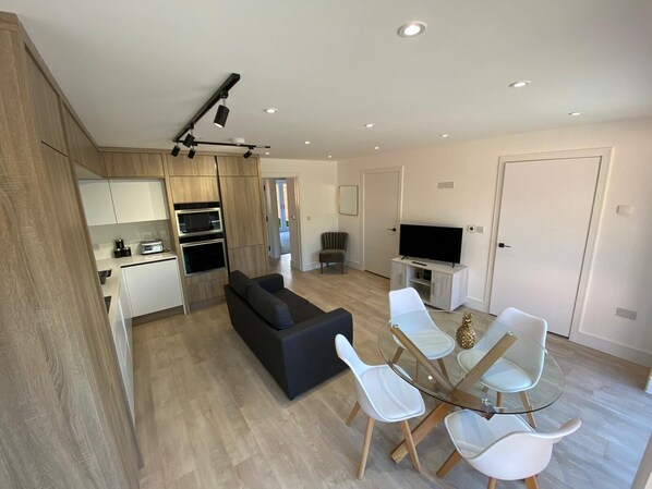 A modern apartment with a kitchen, dining area, living room, and a TV.