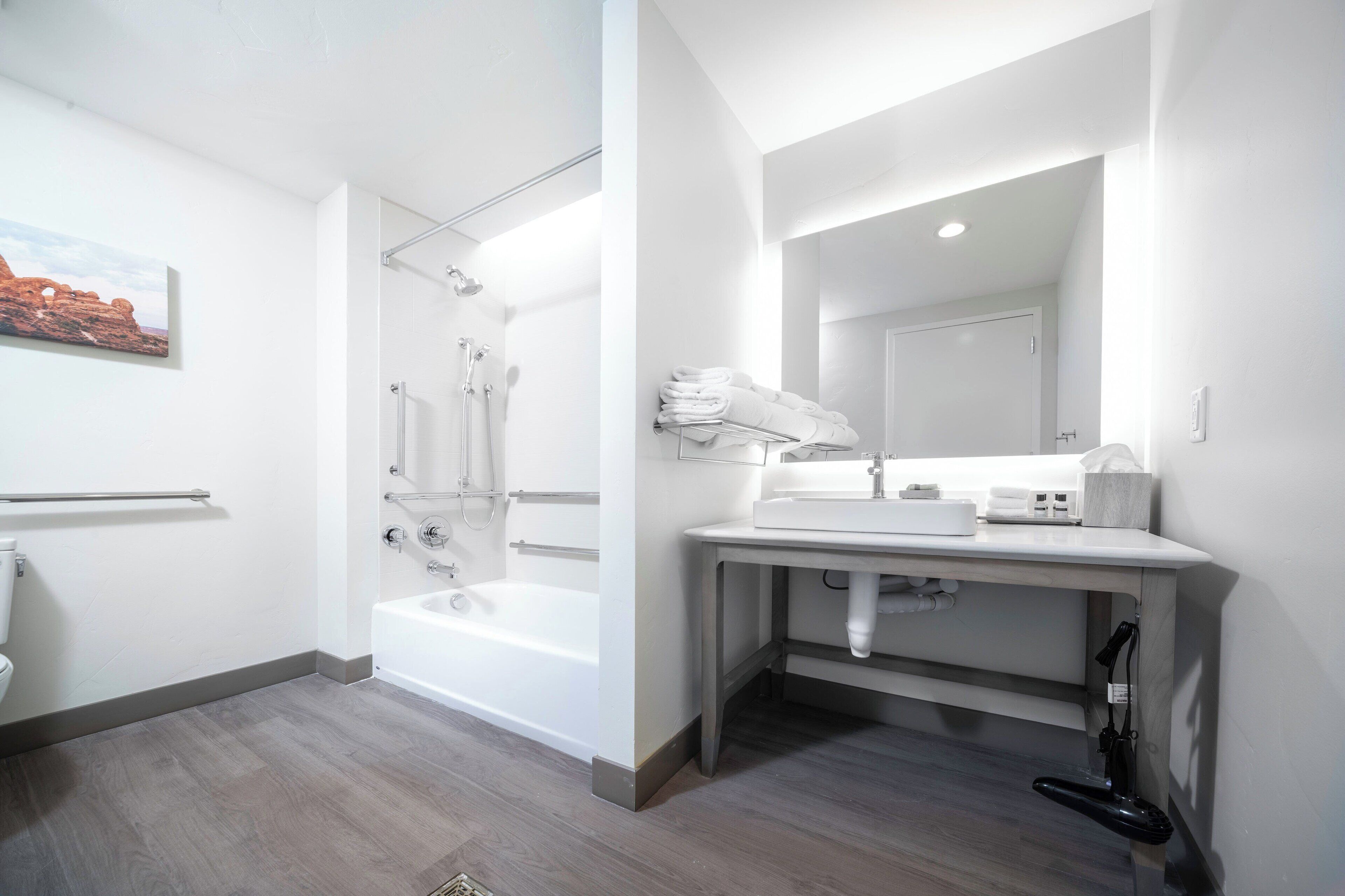 Un baño moderno con una bañera, un lavamanos con espejo y un perchero para toallas.