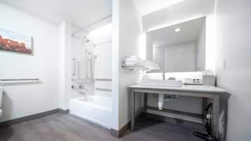 Un baño moderno con una bañera, un lavamanos con espejo y un perchero para toallas.