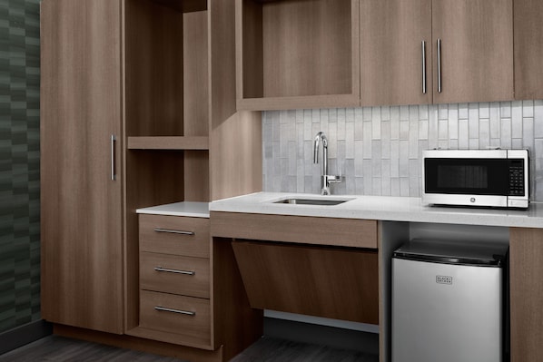 Una cocina con armarios de madera, un microondas de acero inoxidable y un lavavajillas.