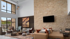 Amplia sala de estar con pared de piedra, ventanas grandes y muebles modernos.