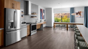 Una cocina moderna con electrodomésticos de acero inoxidable, armarios de madera y una zona de comedor con una mesa larga y sillas.