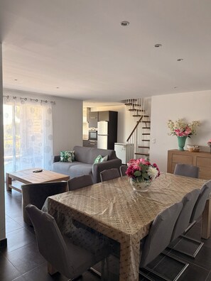 Un salon moderne avec une table à manger, un canapé et une cuisine en arrière-plan.