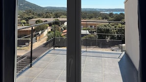 En balkon med udsigt over et boligområde, et bjerg og et vandområde.
