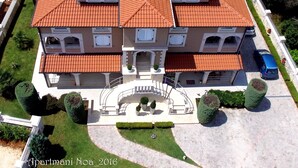 A multi-story building with a red-tiled roof, a central staircase, and a paved driveway. - Studio apartment Sweetie with pool (Funtana)