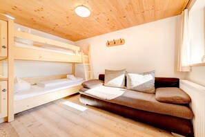 Una habitación con literas, un sofá y techo de madera.