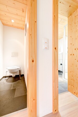 Un baño con inodoro, toallero y puerta de madera.