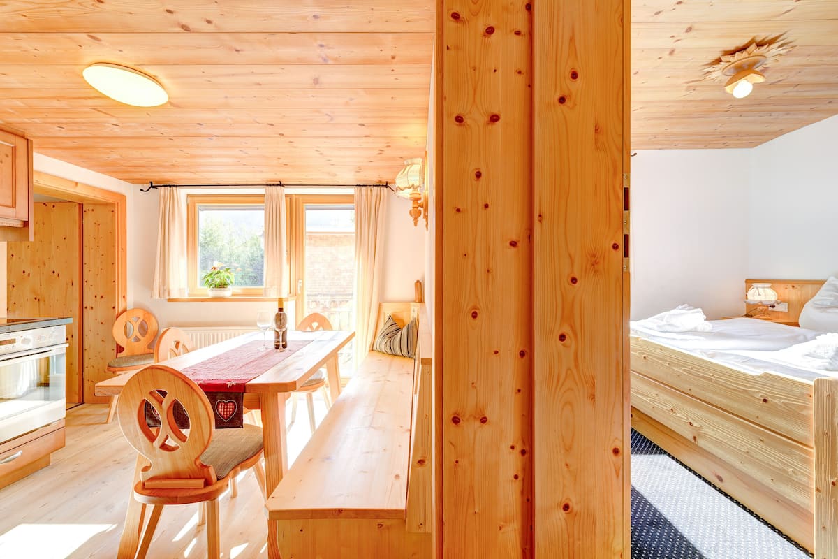 Un intérieur en bois comprenant un coin repas, une cuisine et une chambre.