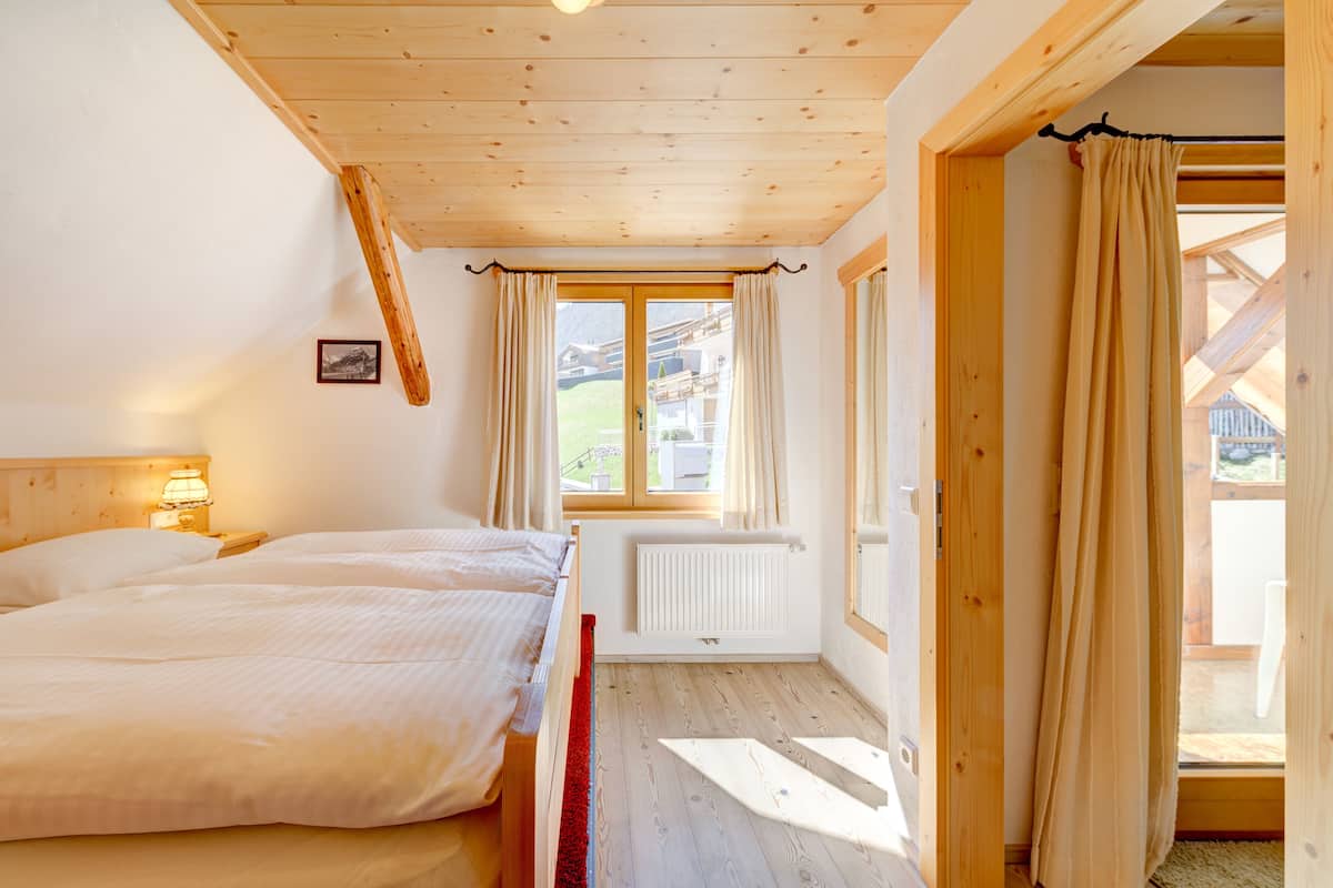 Une pièce en bois avec deux lits, une fenêtre avec des rideaux et un radiateur.