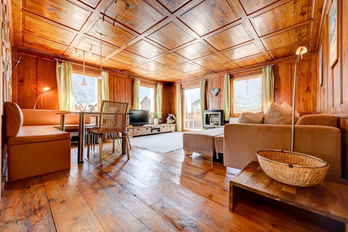 L'intérieur d'un chalet en bois, avec un canapé, un téléviseur et un coin repas.