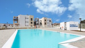En swimmingpool med blå himmel og bygninger i baggrunden.